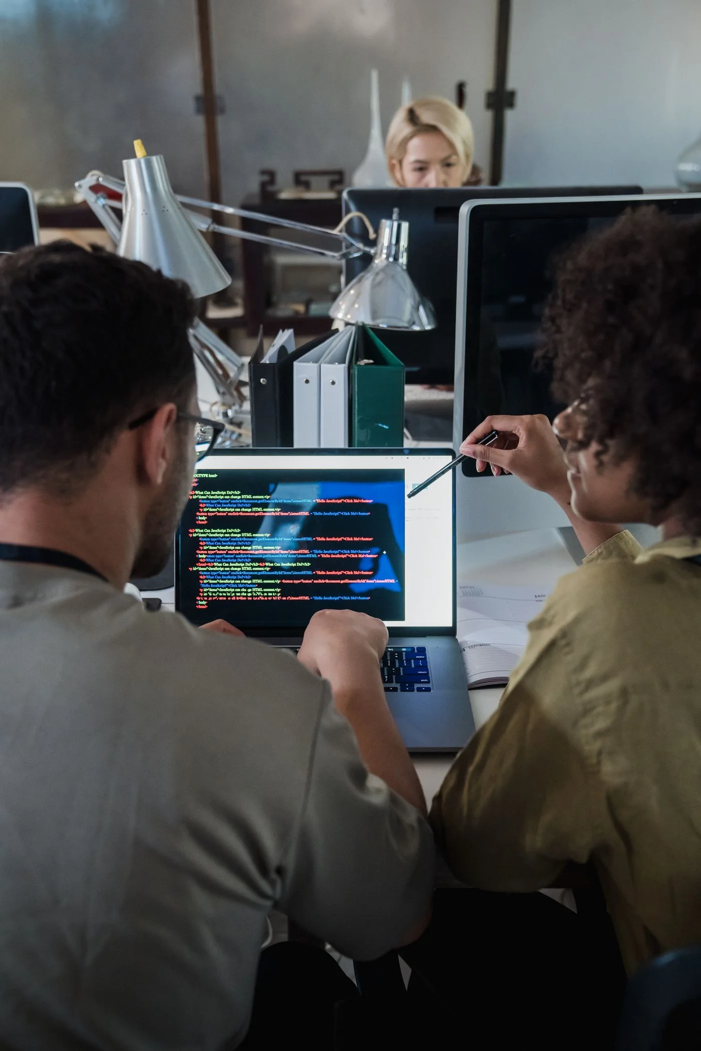 Two developers reviewing application code together on a laptop